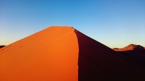 Low angle view of red wall against clear blue sky