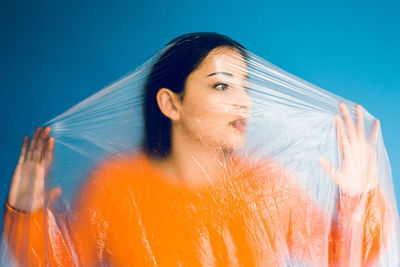 Woman covered in plastic standing against blue background