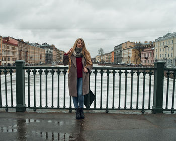 Full length of woman standing against railing against sky