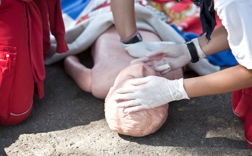 Midsection of paramedic performing cpr on dummy