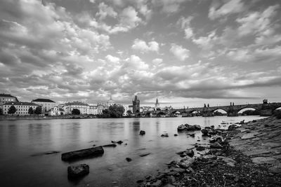 View of city at waterfront against cloudy sky