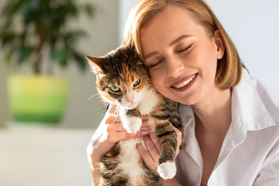 Close-up of smiling woman holding cat at home