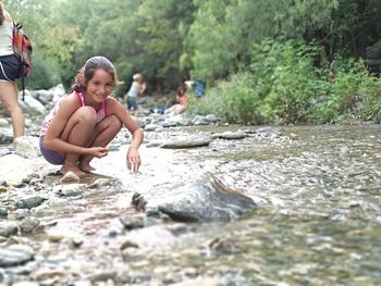 Portrait of girl smiling while crouching in river