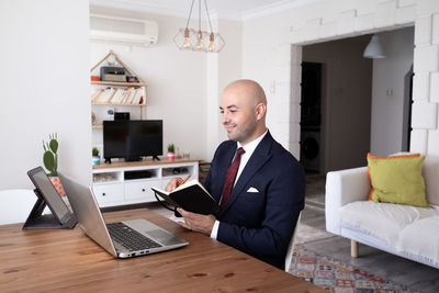 Businessman taking notes, having online meeting in his home office.