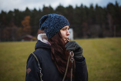 Portrait of young woman looking away while standing on field