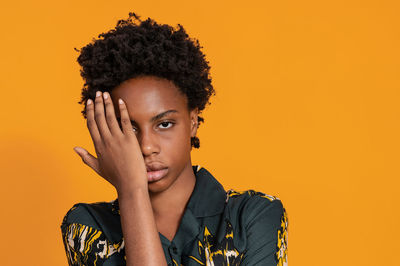 Young woman looking away against yellow background
