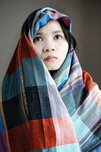 Thoughtful young woman looking away while being covered by textile