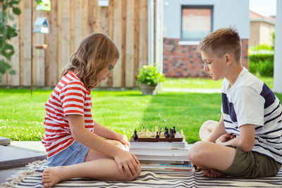 Rear view of boy sitting on boys playing outdoors