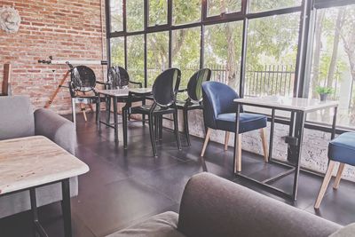 Empty chairs and table against window