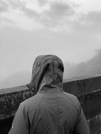 Rear view of woman looking at statue against foggy sky