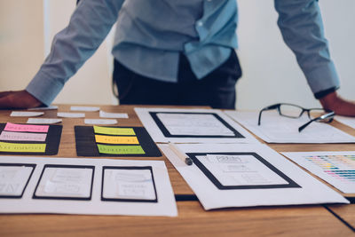 Midsection of businessman with icons on paper at desk