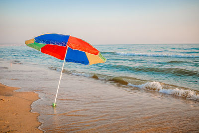 Umbrella on beach against sky