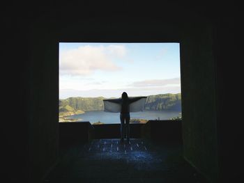 Rear view of woman standing on landscape against sky