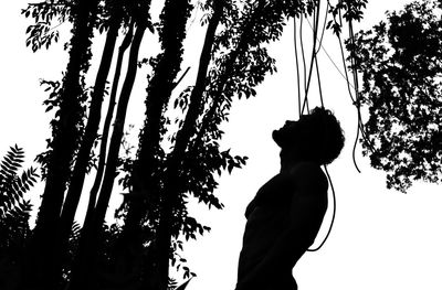 Low angle view of silhouette man standing by tree against sky