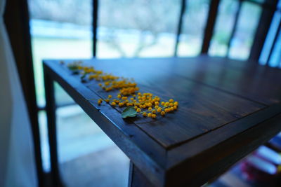Close-up of yellow flower on table by window