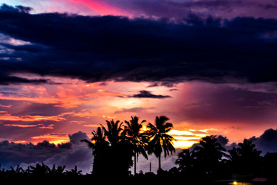 Low angle view of silhouette trees against dramatic sky