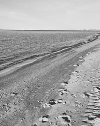 Tire tracks on beach against sky