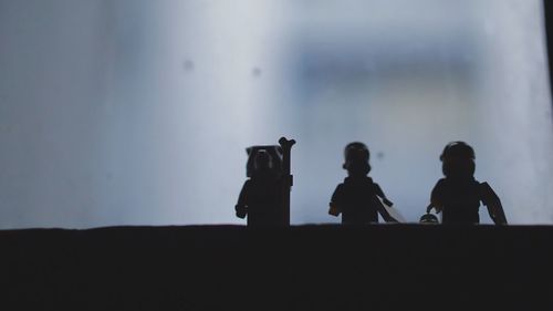 Close-up of silhouette figurines by window at home