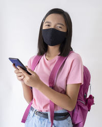 Young woman using phone while standing against white background