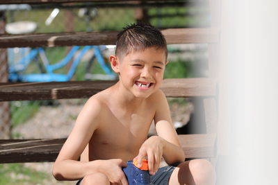 Portrait of shirtless boy sitting on wooden steps