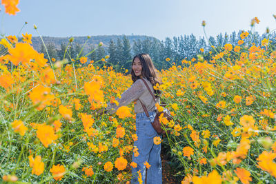 Portrait of woman standing by yellow flowering plants