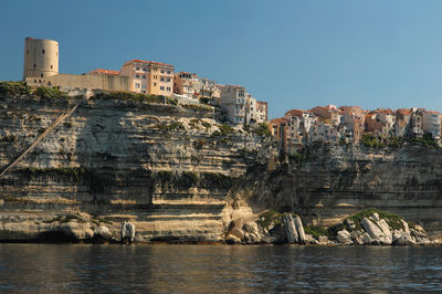 Buildings by sea against clear sky