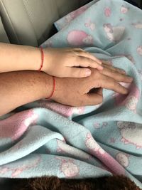 Close-up of kid hand on parent over bedsheet