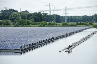 Lake with floating solar panels in a green landscape with electricity pylons