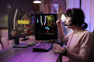 Side view of young woman using laptop at table