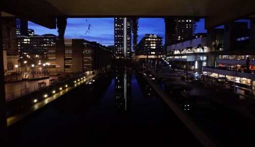 Illuminated bridge over river in city at night