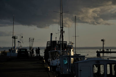 Sailboats moored in sea against sky at sunset