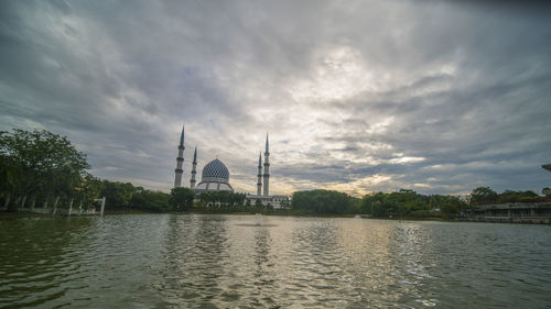 Scenic view of lake by temple against sky