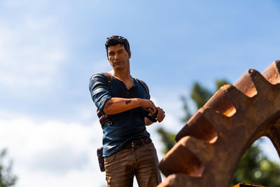 Low angle view of young man looking away against sky