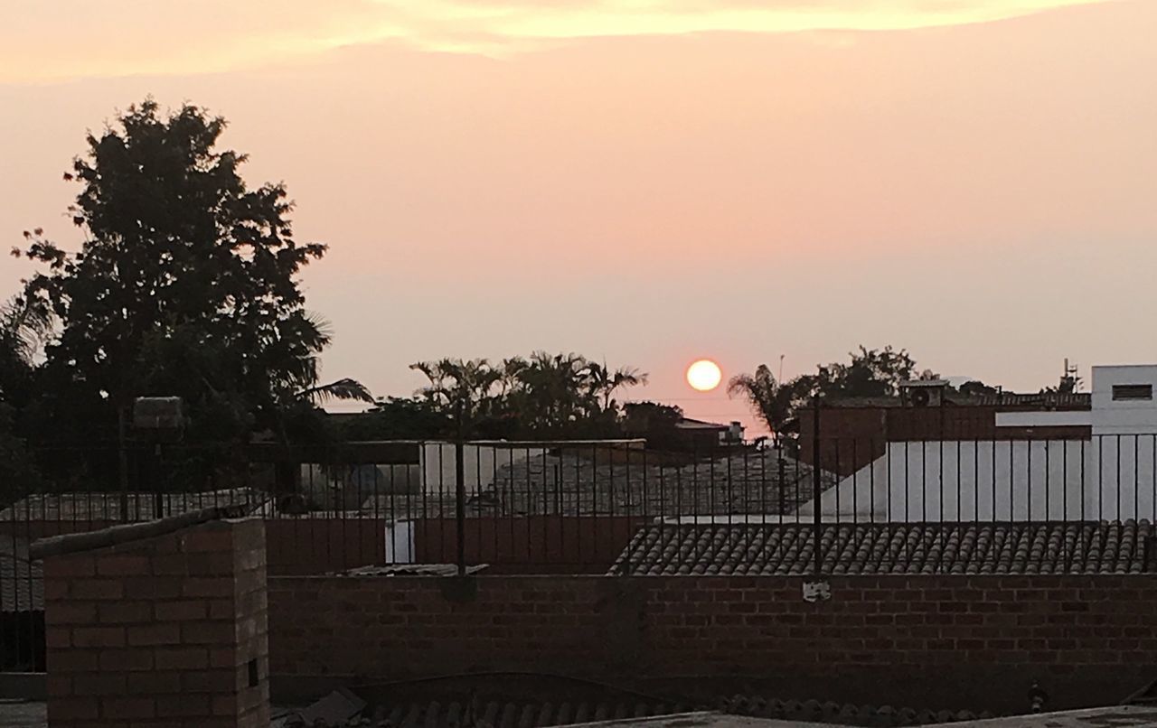 HOUSES BY STREET AGAINST SKY DURING SUNSET