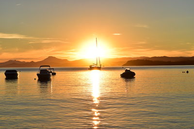 Boats in sea against sky during sunset