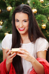 Portrait of a smiling young woman holding christmas tree