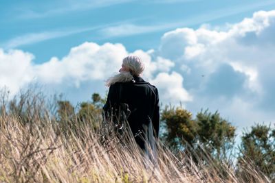 Rear view of man looking at plants against sky