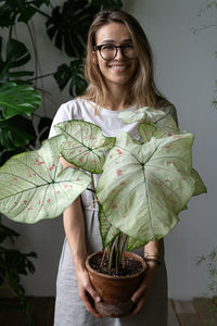 Portrait of smiling woman standing with potted plant