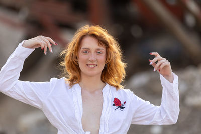 Portrait of smiling young woman standing against wall