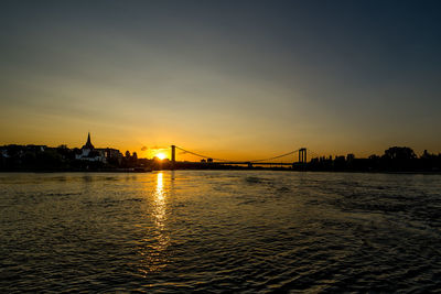 View of suspension bridge over river during sunset