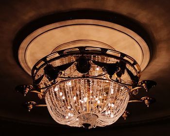 Low angle view of illuminated light bulb hanging from ceiling