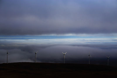 Low angle view of windmills on field against sky