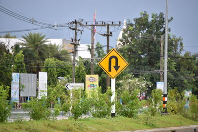 Road sign by trees against sky