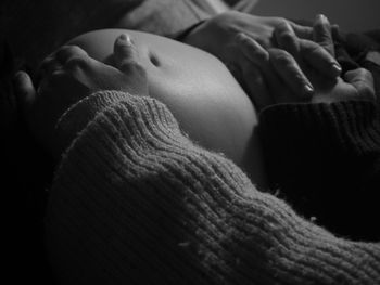 Cropped hand of person touching abdomen of pregnant woman