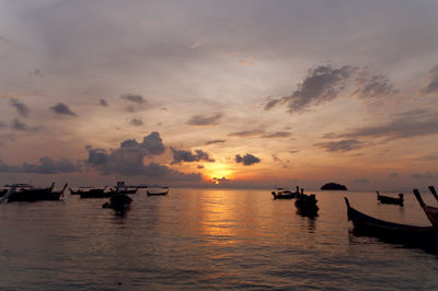 Boats in calm sea at sunset