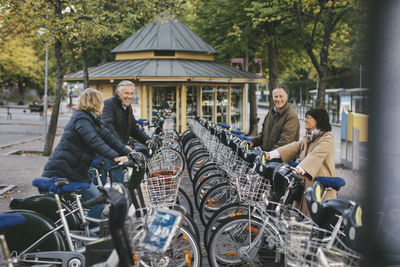 Two senior couples taking rental bikes at parking lot