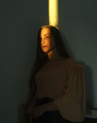 Portrait of beautiful young woman standing against wall