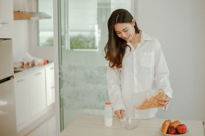 Young woman holding ice cream at home