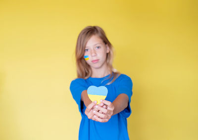 Portrait of smiling girl standing against yellow background