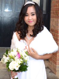 Portrait of young woman standing against wall